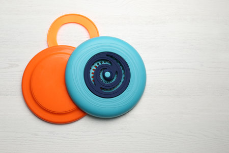 Plastic frisbee disks and ring on white wooden background, flat lay. Space for textの写真素材