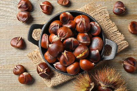 Tasty roasted edible chestnuts on wooden table, flat layの写真素材