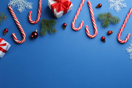 Flat lay composition with candy canes and Christmas decor on blue background. Space for textの写真素材