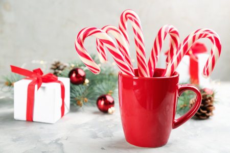 Many sweet candy canes, gift box and Christmas decor on light table. Space for textの写真素材