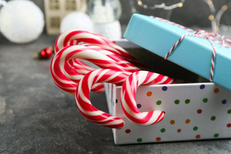 Many sweet candy canes in gift box on grey table, closeup. Traditional Christmas treatの写真素材