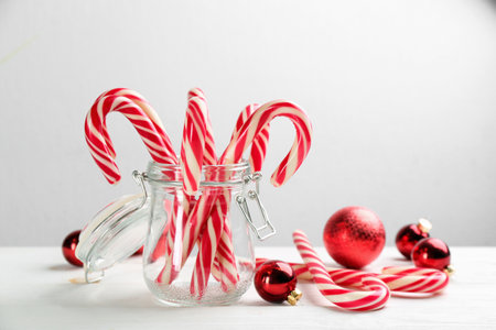 Many sweet candy canes and Christmas decor on white wooden table. Space for textの写真素材