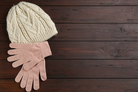 Stylish gloves and hat on wooden background, flat lay. Space for textの写真素材