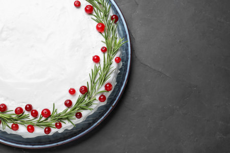 Traditional Christmas cake decorated with rosemary and cranberries on dark grey table, top viewの写真素材