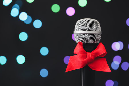 Microphone with red bow against blurred lights, space for text. Christmas musicの写真素材