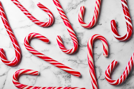 Sweet Christmas candy canes on white marble background, flat layの写真素材