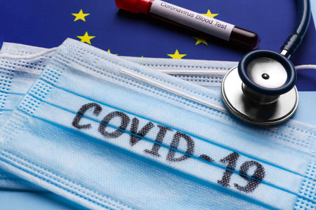 Protective masks, stethoscope and test tube with blood sample on European Union flag background, closeup. coronavirus outbreakの写真素材