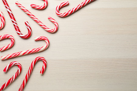 Sweet Christmas candy canes on wooden background, flat lay. Space for textの写真素材