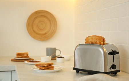 Modern toaster and tasty breakfast on counter in kitchenの写真素材