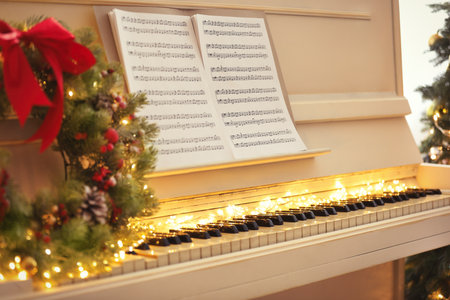 White piano with fairy lights and note sheets indoors, closeup. christmas musicの写真素材