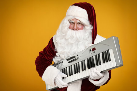 Santa Claus with synthesizer on yellow background. christmas musicの写真素材