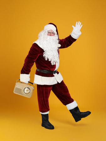 Santa Claus with vintage radio on yellow background. christmas musicの写真素材