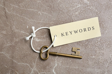 Vintage key and tag wIth word KEYWORDS on gray table, top viewの写真素材