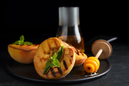 Delicious grilled peaches with honey and mint on black tableの写真素材