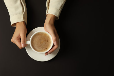 Woman with cup of coffee on black background, top view. Space for textの写真素材
