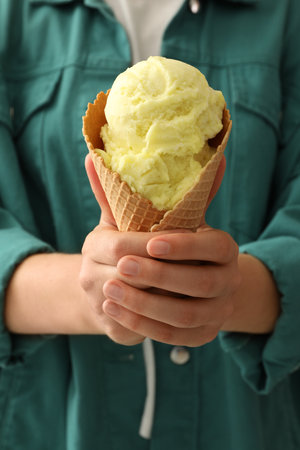 Woman holding yellow ice cream in wafer cone, closeupの写真素材