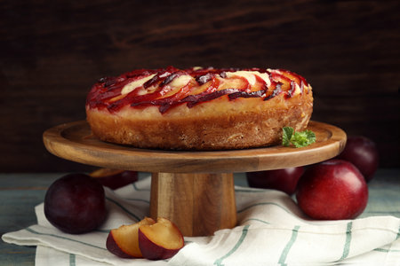 Delicious pie with plums on wooden cake standの写真素材