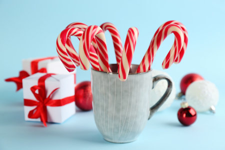 Christmas candy canes in cup on light blue backgroundの写真素材