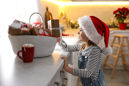 Cute little girl in Santa hat taking gift from Christmas advent calendar at homeの写真素材