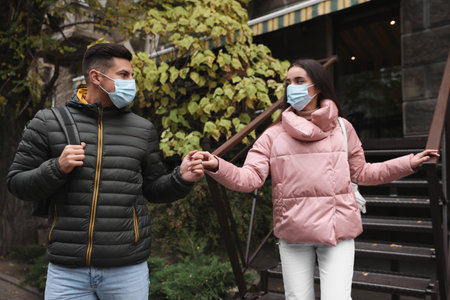 Couple in medical face masks walking outdoors. Personal protection during COVID-19 pandemicの写真素材