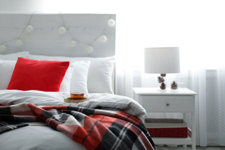 Comfortable bed with warm checkered plaid in stylish room interiorの写真素材