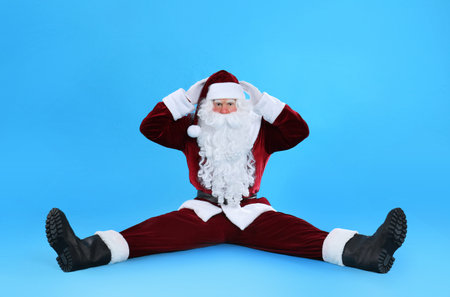 Funny Santa Claus sitting on light blue backgroundの写真素材