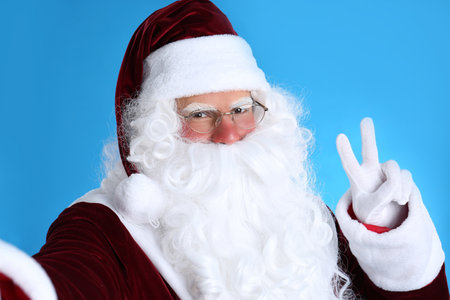 Santa Claus taking selfie on light blue backgroundの写真素材