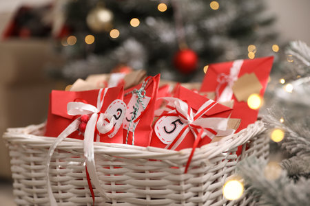 Basket full of gifts in paper bags for Christmas advent calendar on blurred background, closeupの写真素材