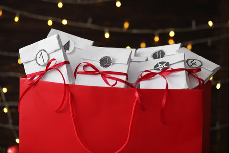 Set of gifts in red bag against blurred lights, closeup. christmas advent calendarの写真素材