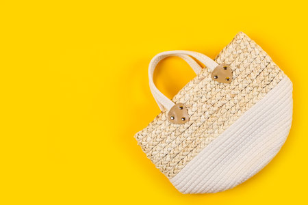 Stylish woman's straw bag on yellow background, top view. Space for textの写真素材