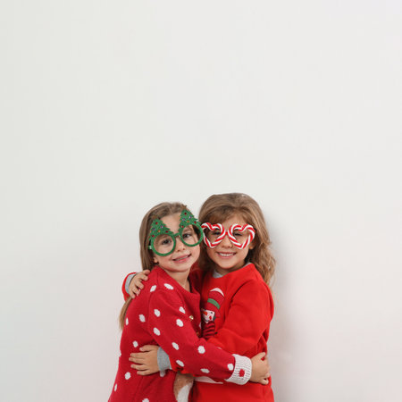 Kids in Christmas sweaters and festive glasses on white backgroundの写真素材