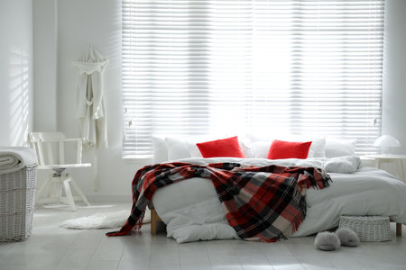 Comfortable bed with warm checkered plaid in stylish room interiorの写真素材