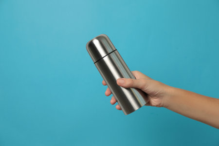 Woman holding modern thermos on light blue background, closeupの写真素材