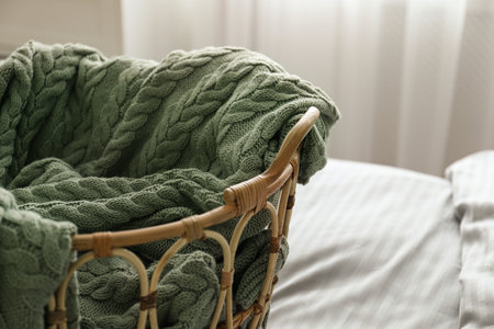Knitted green plaid in wicker basket on bed indoors, closeupの写真素材