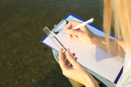 Scientist with clipboard and sample taken from river, closeupの写真素材