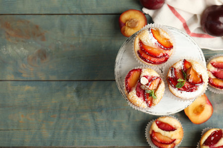 Delicious sweet cupcakes with plums on wooden table, flat lay. Space for textの写真素材