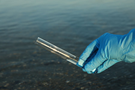 Scientist with test tube taking sample from river for analysis, closeupの写真素材