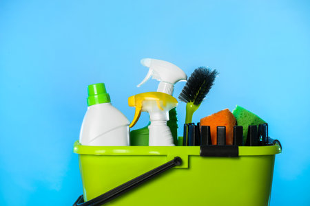 Bucket with different cleaning products and supplies on light blue background, closeupの写真素材
