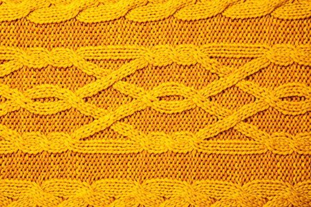 Soft orange knitted plaid as background, top view