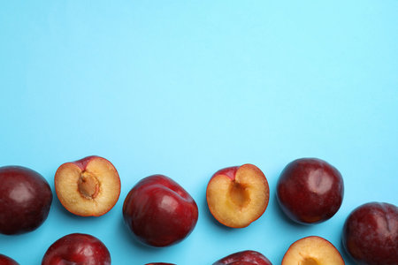 Delicious ripe plums on light blue background, flat lay. Space for textの写真素材