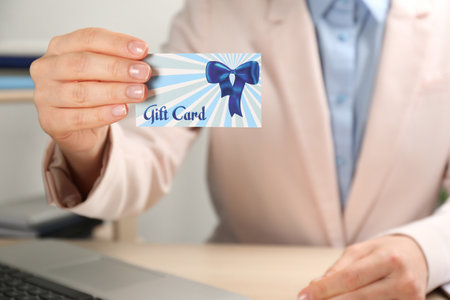 Woman with gift card at table indoors, closeupの写真素材