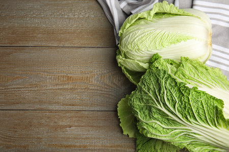 Fresh ripe Chinese cabbages on wooden table, flat lay. Space for textの写真素材