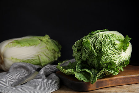 Fresh ripe Chinese cabbages on wooden table against black backgroundの写真素材