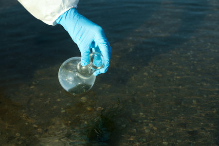 Scientist with florence flask taking sample from river for analysis, closeupの写真素材