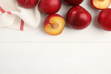 Delicious ripe plums on white wooden table, flat lay. Space for textの写真素材