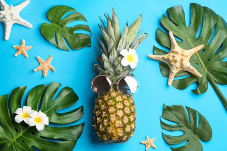 Flat lay composition with pineapple, sunglasses and beach items on light blue background. creative conceptの写真素材