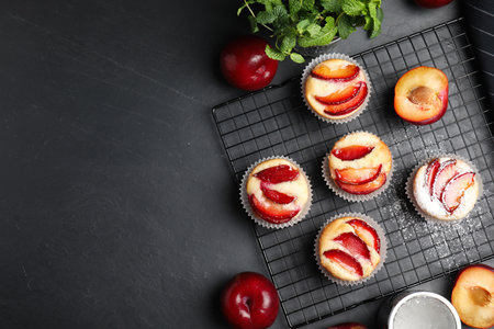 Delicious cupcakes with plums on black table, flat lay. Space for textの写真素材