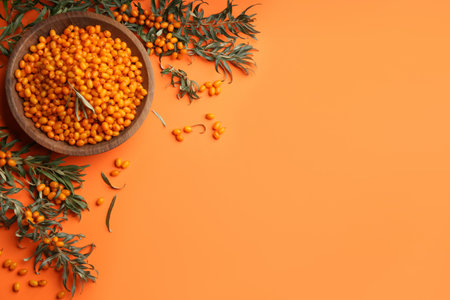 Fresh ripe sea buckthorn on orange background, flat lay. Space for text