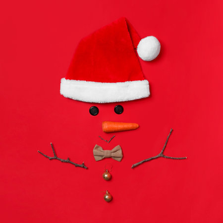 Funny snowman made with different elements on red background, flat layの写真素材