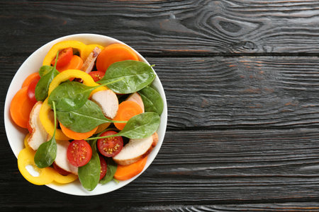 Delicious fresh chicken salad served on black wooden table, top view. Space for textの写真素材